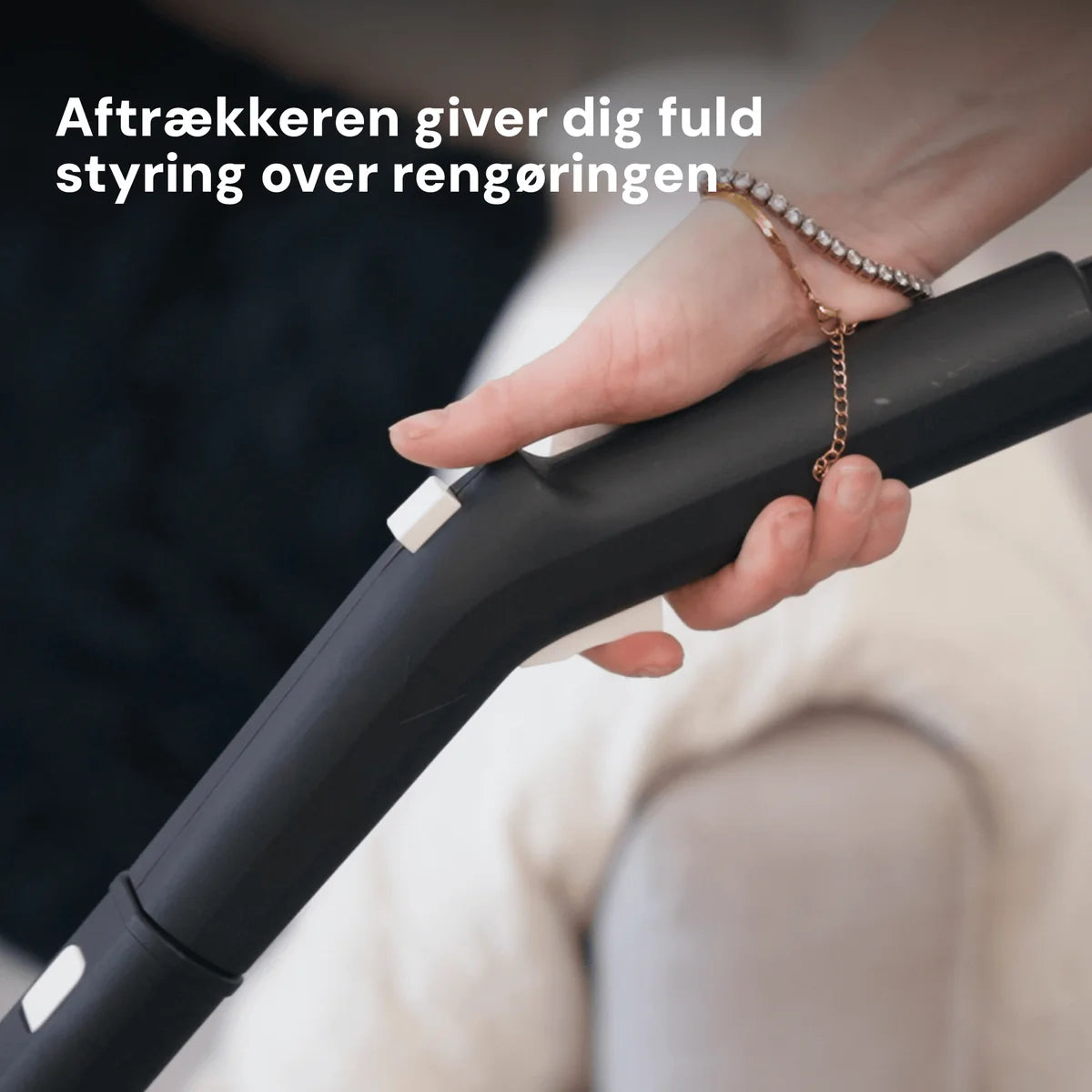 Rennoa SteamCleaner Pro håndholdt damprenser i sort med tilkoblet guldfarvet kjede, holdt i hånd.