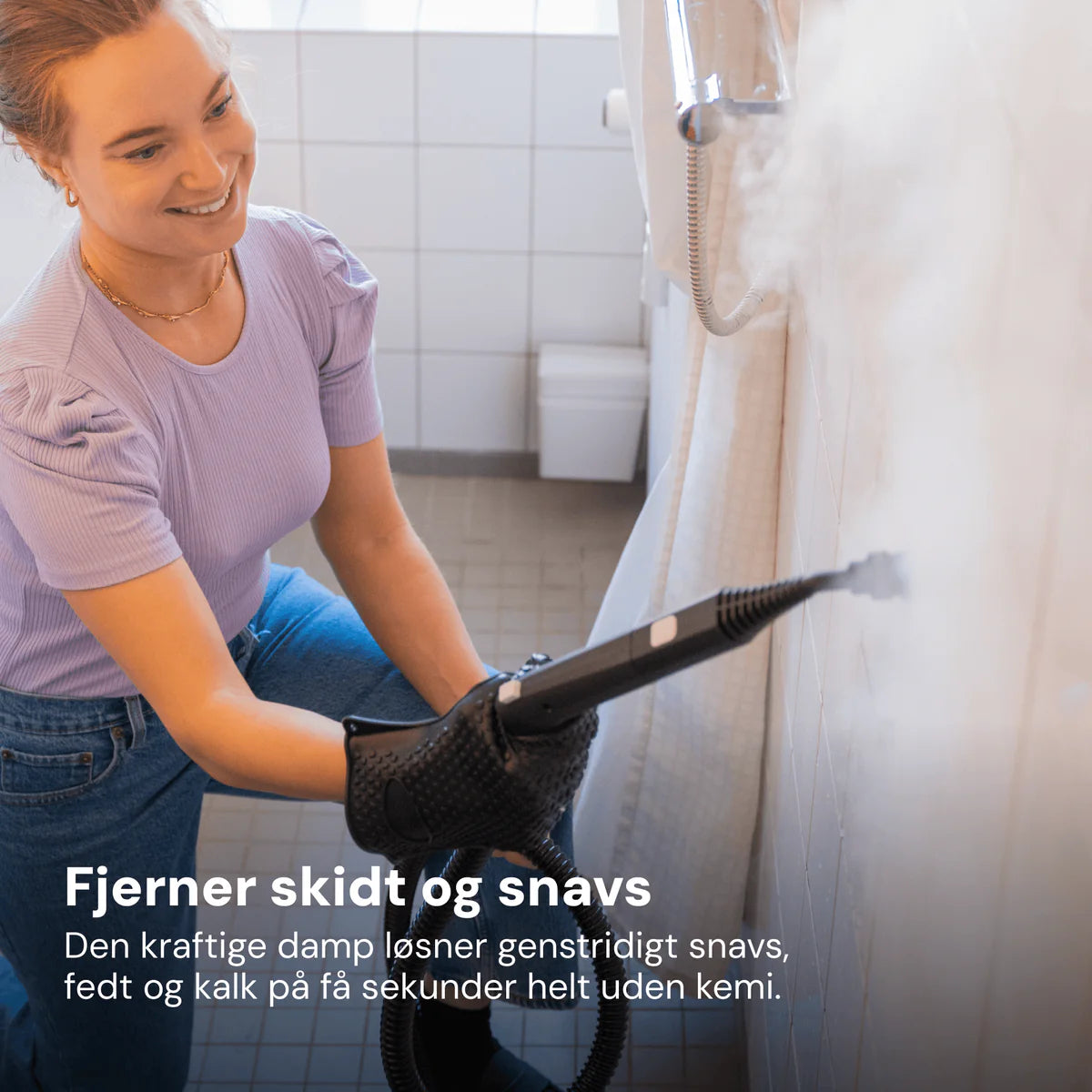 Damprenser med sort håndtag og tilsluttet slange, bruges til rengøring af fliser på badeværelsesvæg.